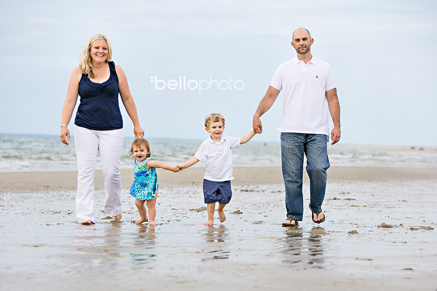 family walking along shore of beach