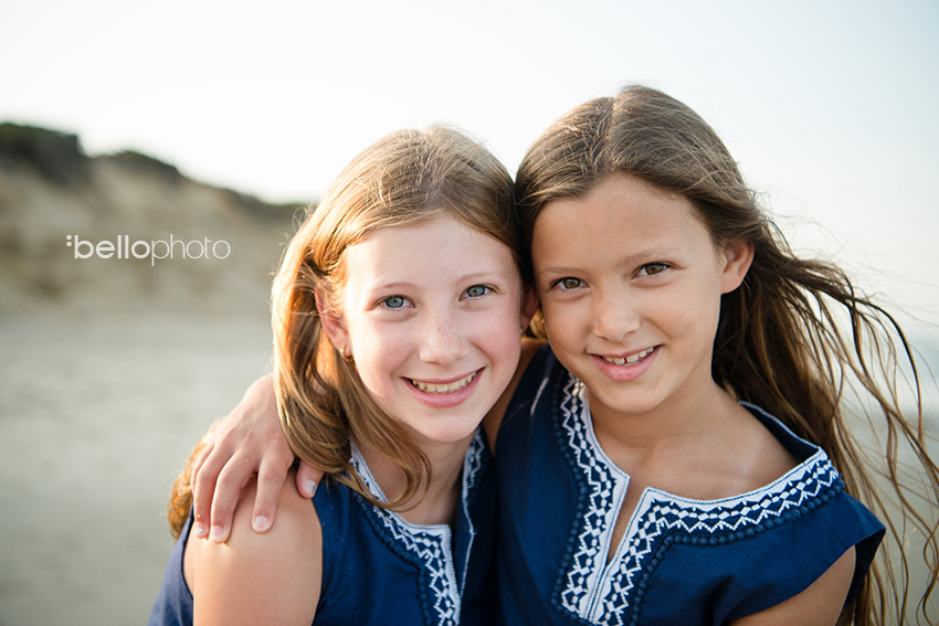 close up photo of sisters at the beach hugging