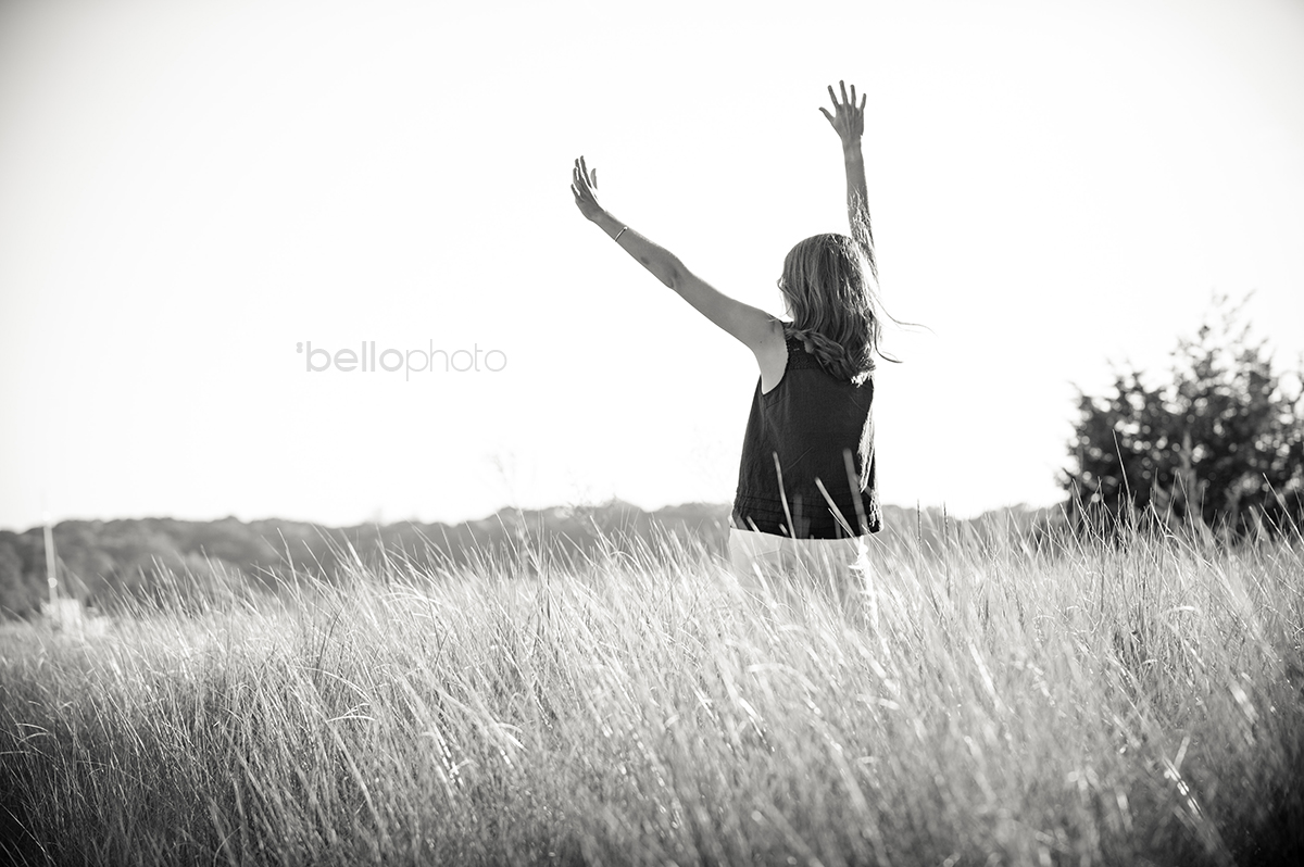 photo of girl in tall beach grass celebrating graduation